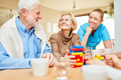 a caregive and senior couple having fun on the living room