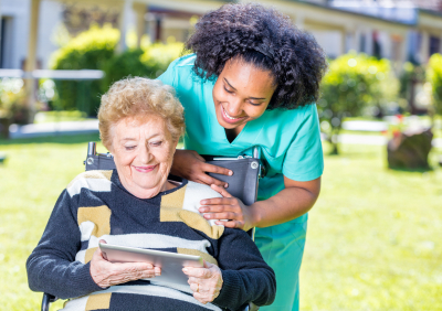 a caregiver and her senior patient watching somethin on the tablet