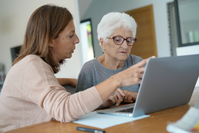 senior woman using laptop with help of homecarer